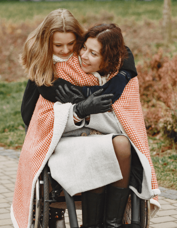 A mother and daughter sharing a warm embrace outdoors